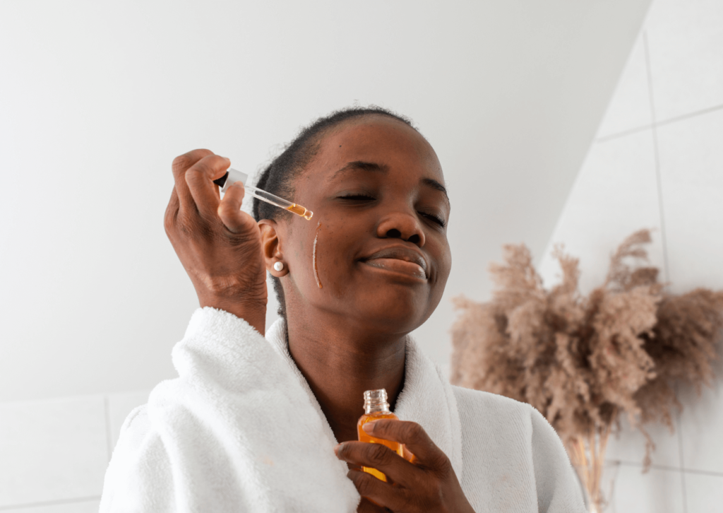 Femme noire qui applique du sérum sur le visage