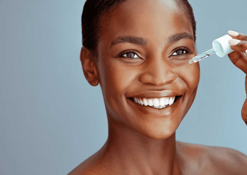 Femme noire qui met du sérum sur son visage